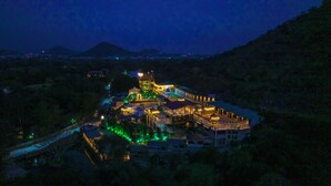A large, illuminated hotel complex with multiple buildings and a prominent central structure. - Badi Garh Resort (Udaipur)