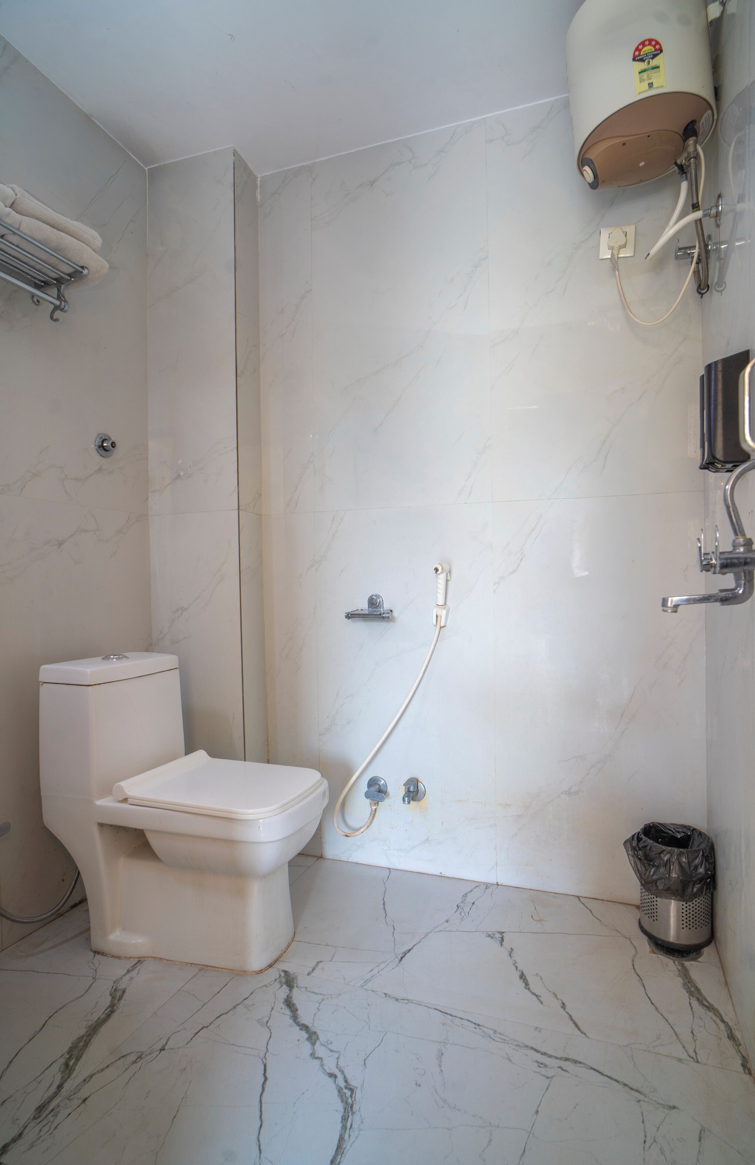 A bathroom with a toilet, a shower, and a marble floor.