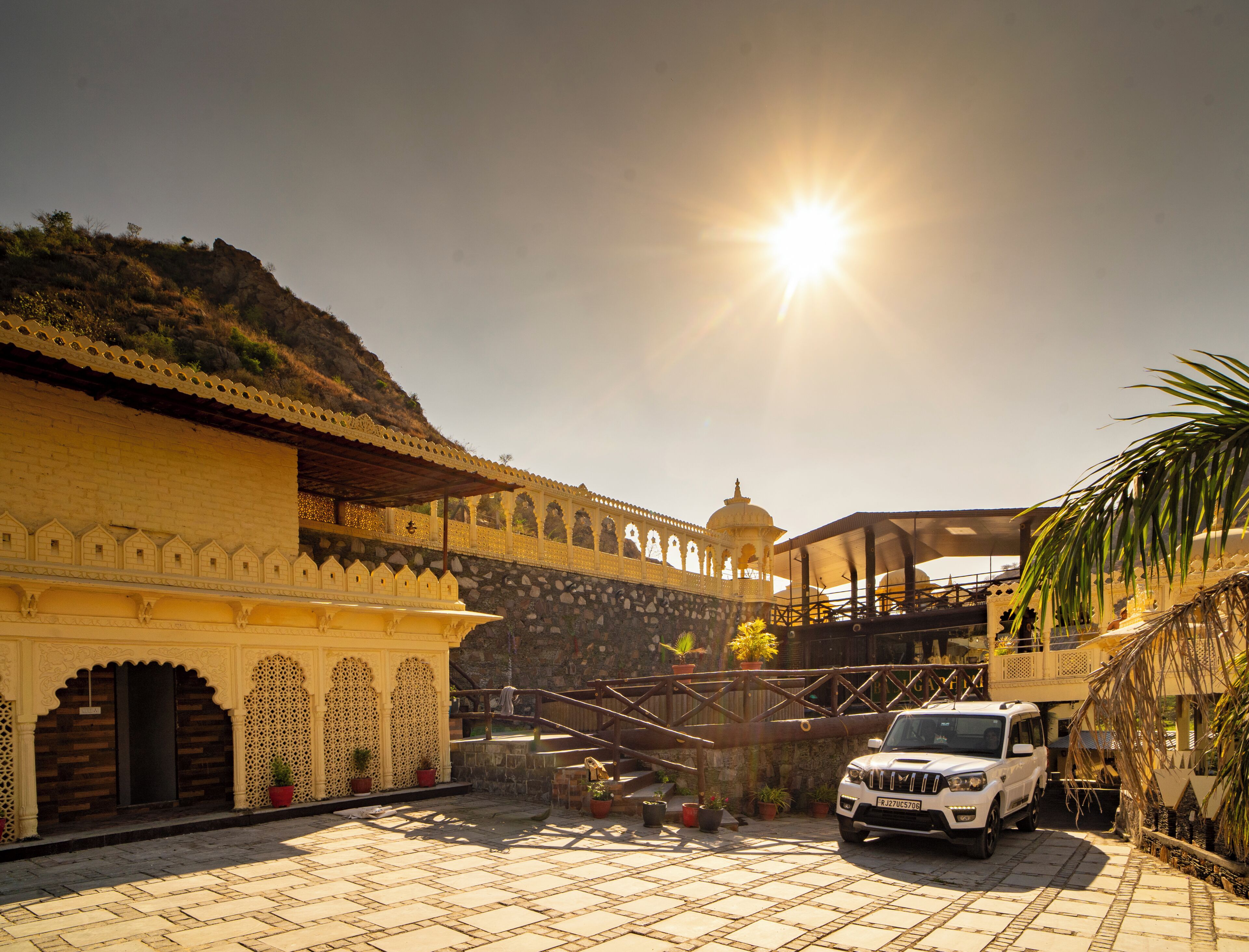 A white SUV parked in front of a building with a dome and a staircase leading up to a terrace.