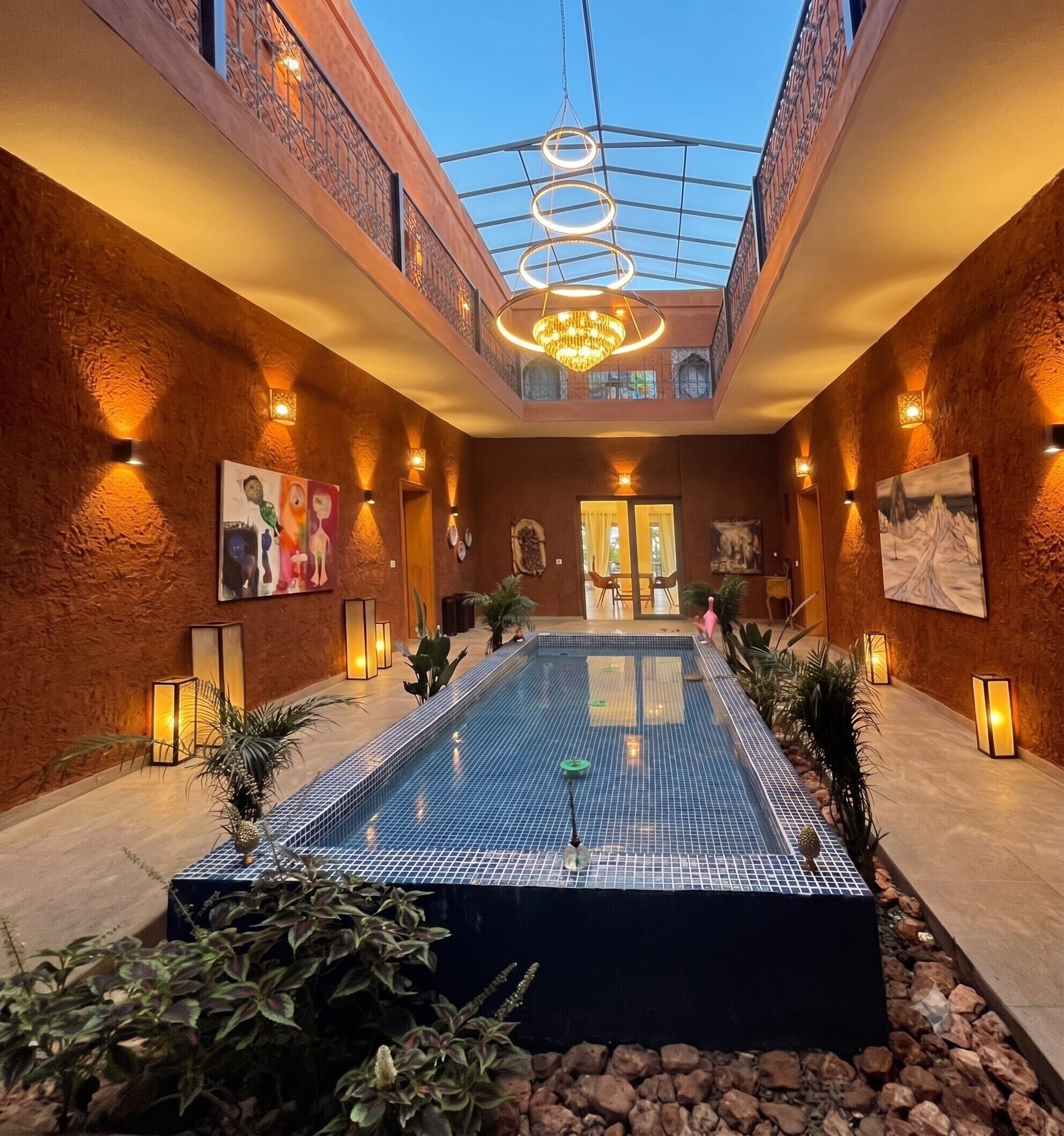 A hotel atrium with a swimming pool, artwork, and a glass ceiling.