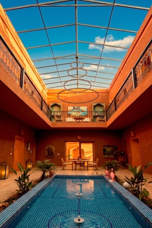 Una piscina con techo de cristal, un comedor y vistas al cielo.