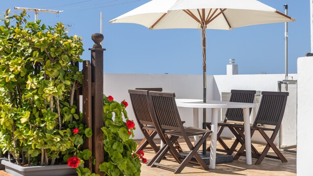 A patio with a table and chairs, a white umbrella, and potted plants. - \"marina house\" conil (Conil de la Frontera)