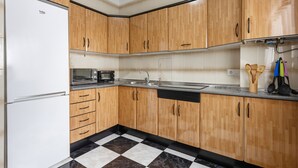 A kitchen with wooden cabinets, a white refrigerator, a microwave, and a sink. - \"marina house\" conil (Conil de la Frontera)