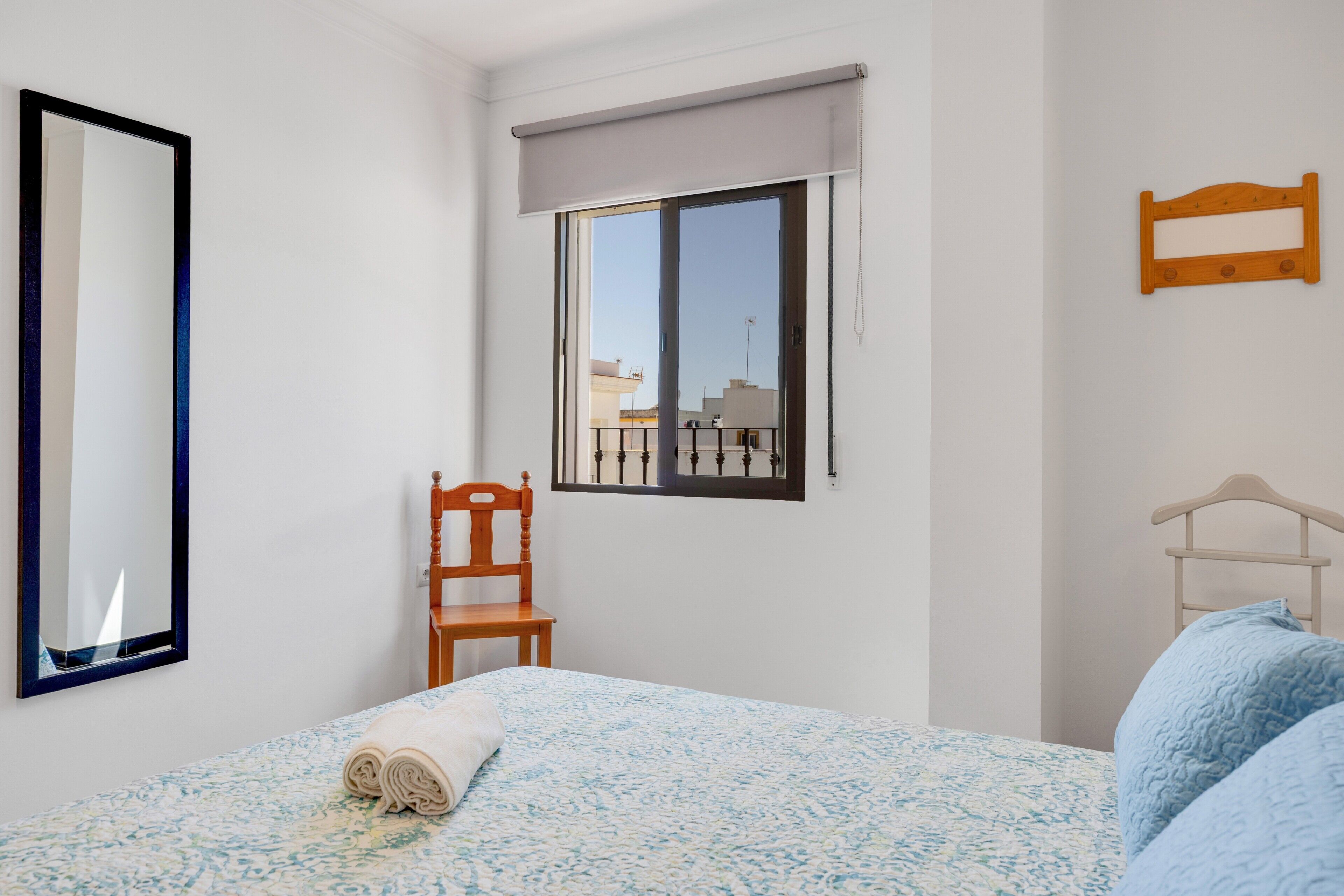 Une chambre à coucher avec un lit, une chaise, une fenêtre et un miroir.