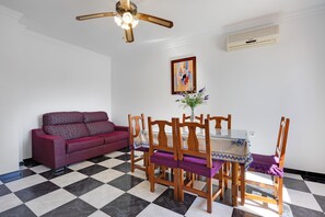 A dining area with a table, chairs, a ceiling fan, and a wall-mounted air conditioner.