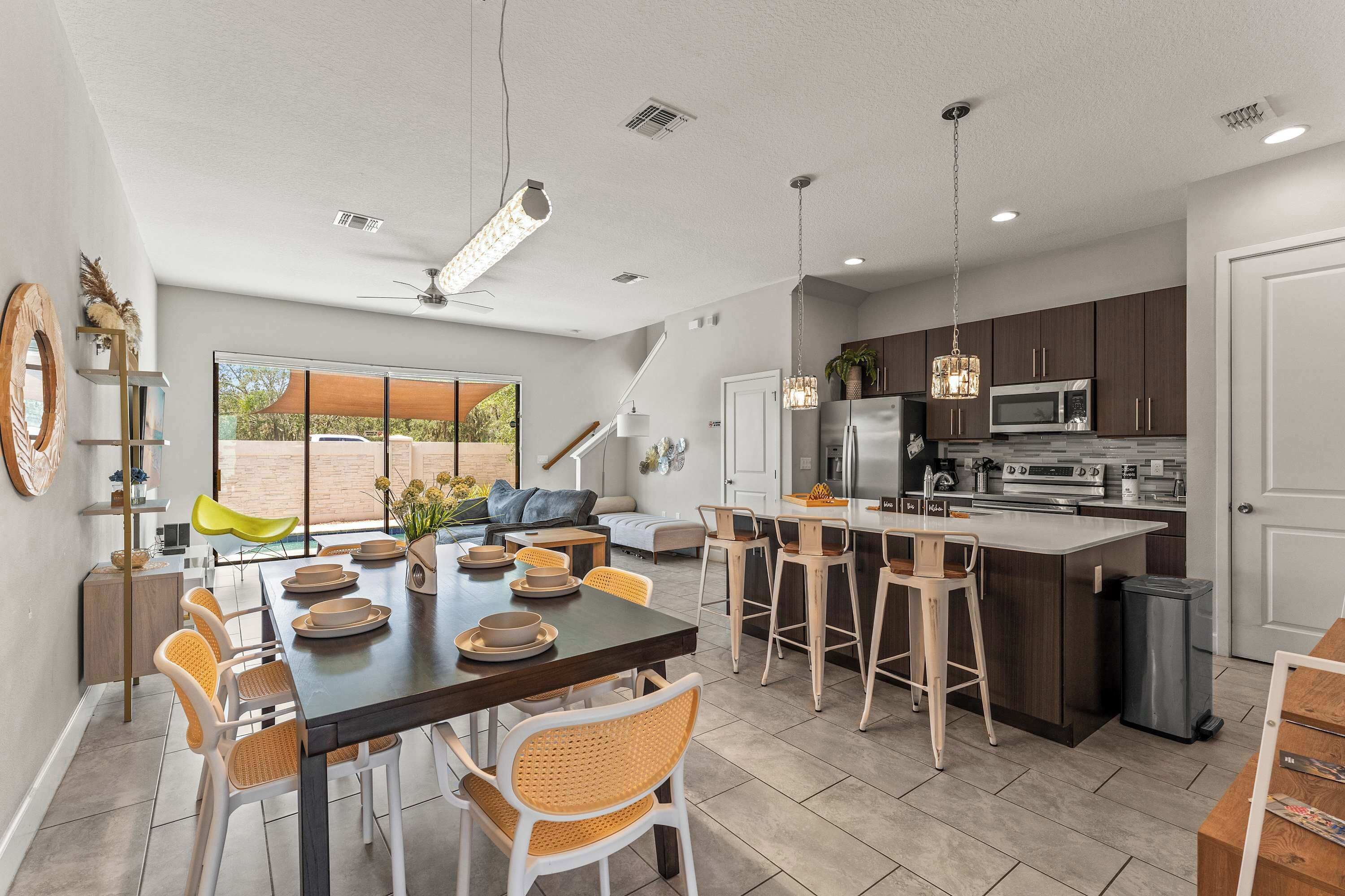 A modern kitchen with a central island, bar stools, and a dining area with a long table and chairs.
