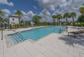 Une piscine à l’eau d’un bleu cristallin, entourée de palmiers et de chaises longues.