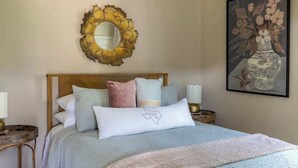 A neatly made bed with a headboard, a round mirror, and a framed artwork on the wall. - Countryside Escape | 5 minutes to Round Top | 2BR (Round Top)