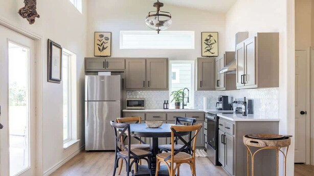 A modern kitchen with a central island, stainless steel appliances, and a dining area with wooden chairs. - 2 Bedrooms + Full Kitchen + 5 min drive to RT (Round Top)