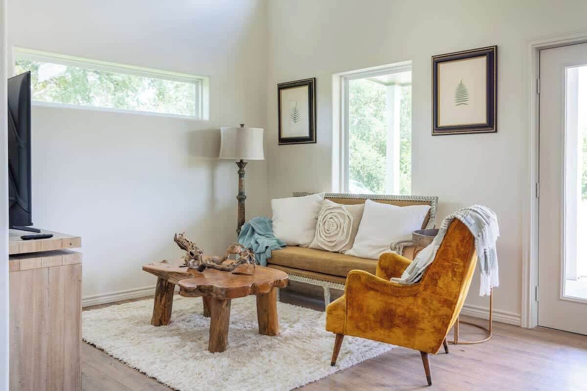 Un salón acogedor con sofá, sillón, mesa de centro de madera y televisor sobre un mueble.