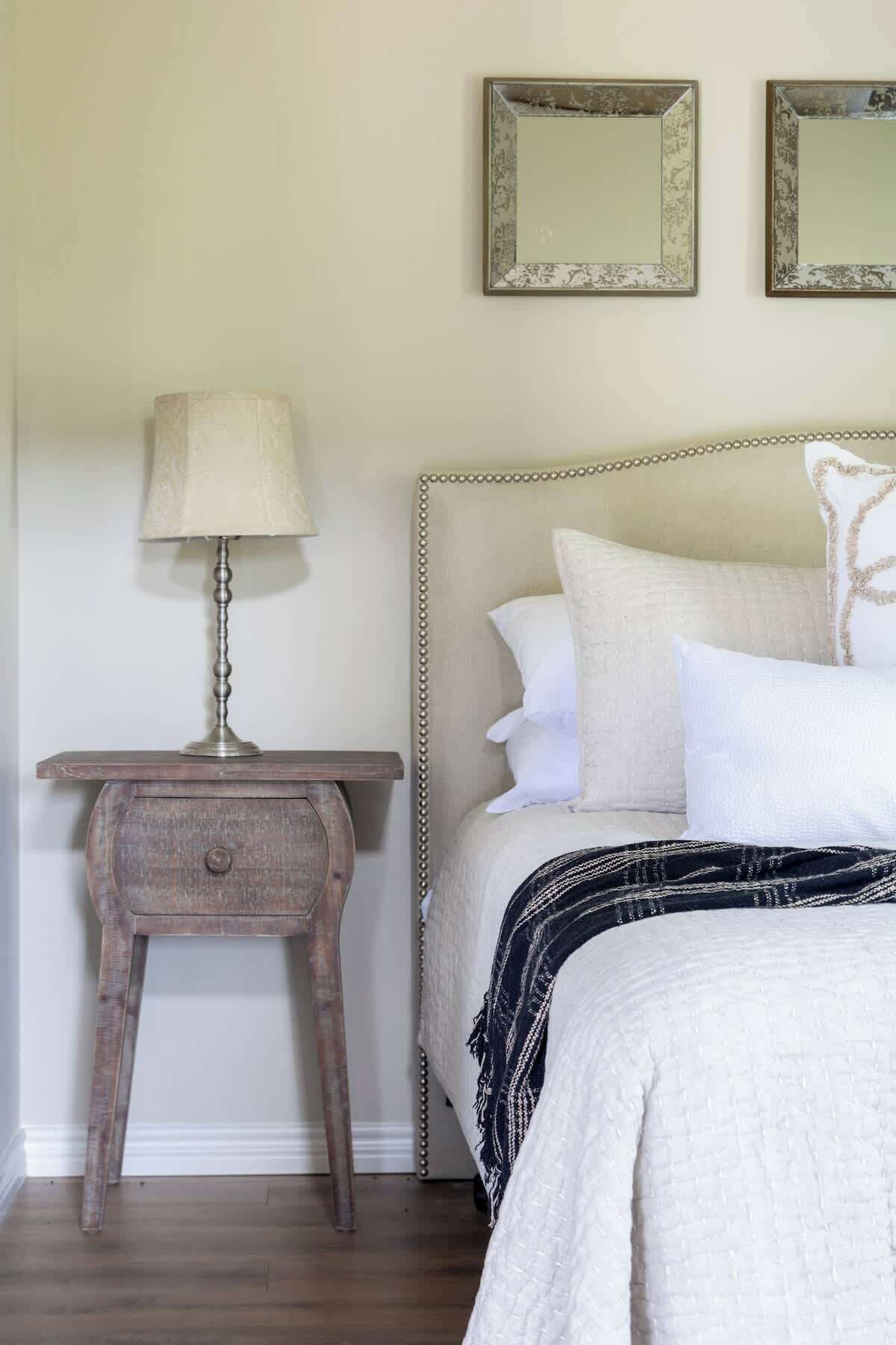 Une chambre à coucher comprenant un lit, une table de chevet et deux miroirs fixés au mur.