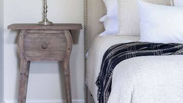 Une chambre à coucher comprenant un lit, une table de chevet et deux miroirs fixés au mur.