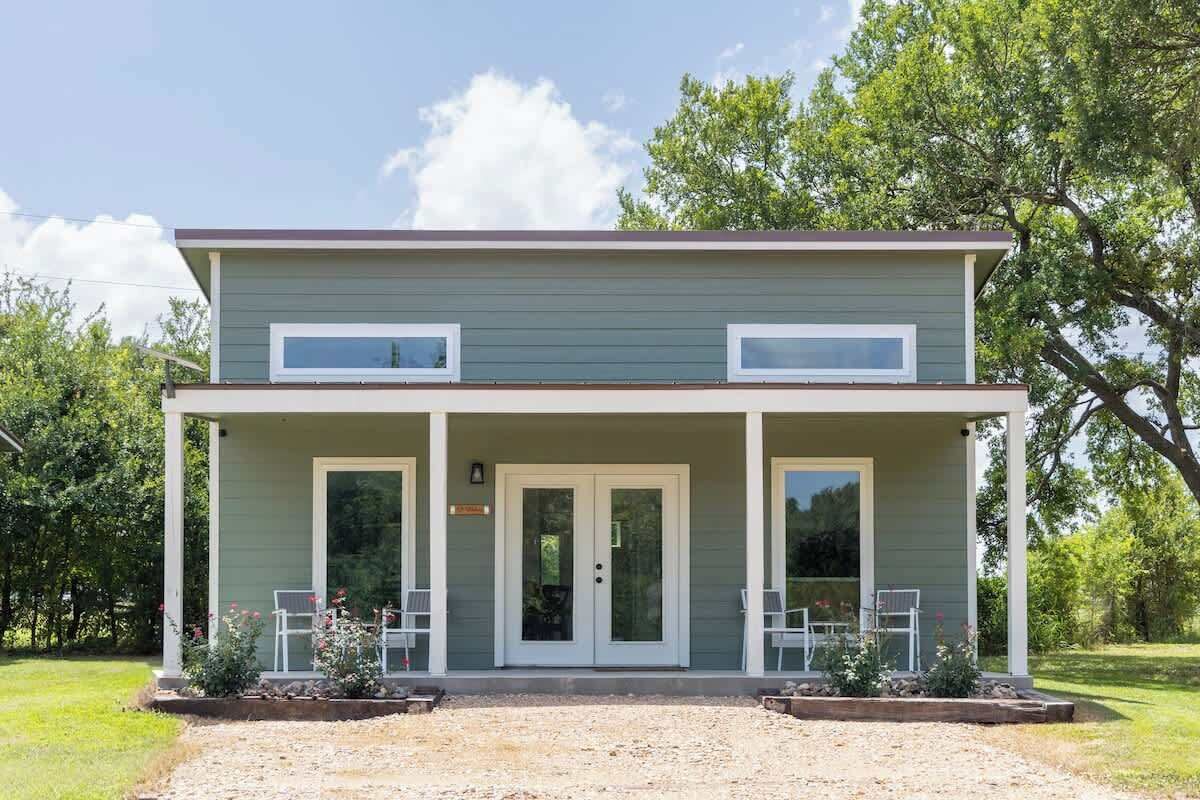Une maison à deux étages avec un porche couvert, une porte d’entrée et deux fenêtres à l’étage supérieur.