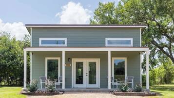 Une maison à deux étages avec un porche couvert, une porte d’entrée et deux fenêtres à l’étage supérieur.