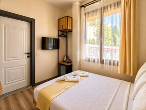A hotel room with a bed, a television mounted on the wall, a small table with a kettle, and a window with curtains. - The Little Prince Hotel (Antalya)