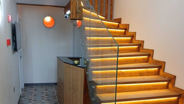 A staircase with wooden steps and glass railings, leading to a landing with a flat ceiling and a wall-mounted television. - The Little Prince Hotel (Antalya)