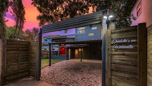 A modern building with a blue facade, a red door, and a wooden gate. - East Austin Modern | Rooftop Deck | Walk to Bars (Austin)