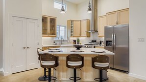A modern kitchen with a central island, bar stools, stainless steel appliances, and a window providing natural light. - East Austin Modern | Rooftop Deck | Walk to Bars (Austin)