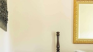 A bedroom with a wooden nightstand, a bed with an orange quilt, and a lamp. - Hidden Gem Near Round Top | 2BR Cottage (Round Top)