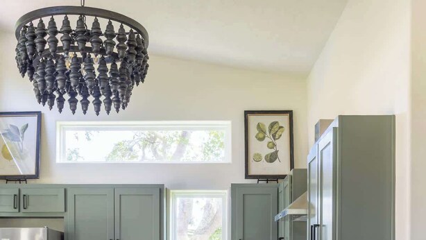 A modern kitchen with grey cabinets, a central island, a dining table with chairs, and a chandelier. - Hidden Gem Near Round Top | 2BR Cottage (Round Top)