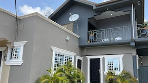 A two-story house with a balcony, satellite dish, and a front door.
