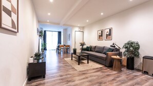 Un salon moderne avec un canapé, une table basse et une table d’appoint. On aperçoit à l’arrière-plan un coin repas avec une table et des chaises.