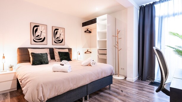 Une chambre à coucher moderne, comprenant un lit, des tables de chevet, une armoire et un bureau.