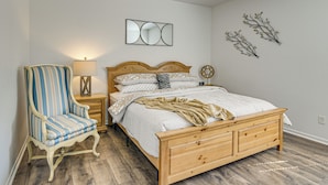 A bedroom with a wooden bed, a striped armchair, a bedside table with a lamp, and wall art. - Family-friendly Houston Home: Soccer Fans Welcome! (Houston)