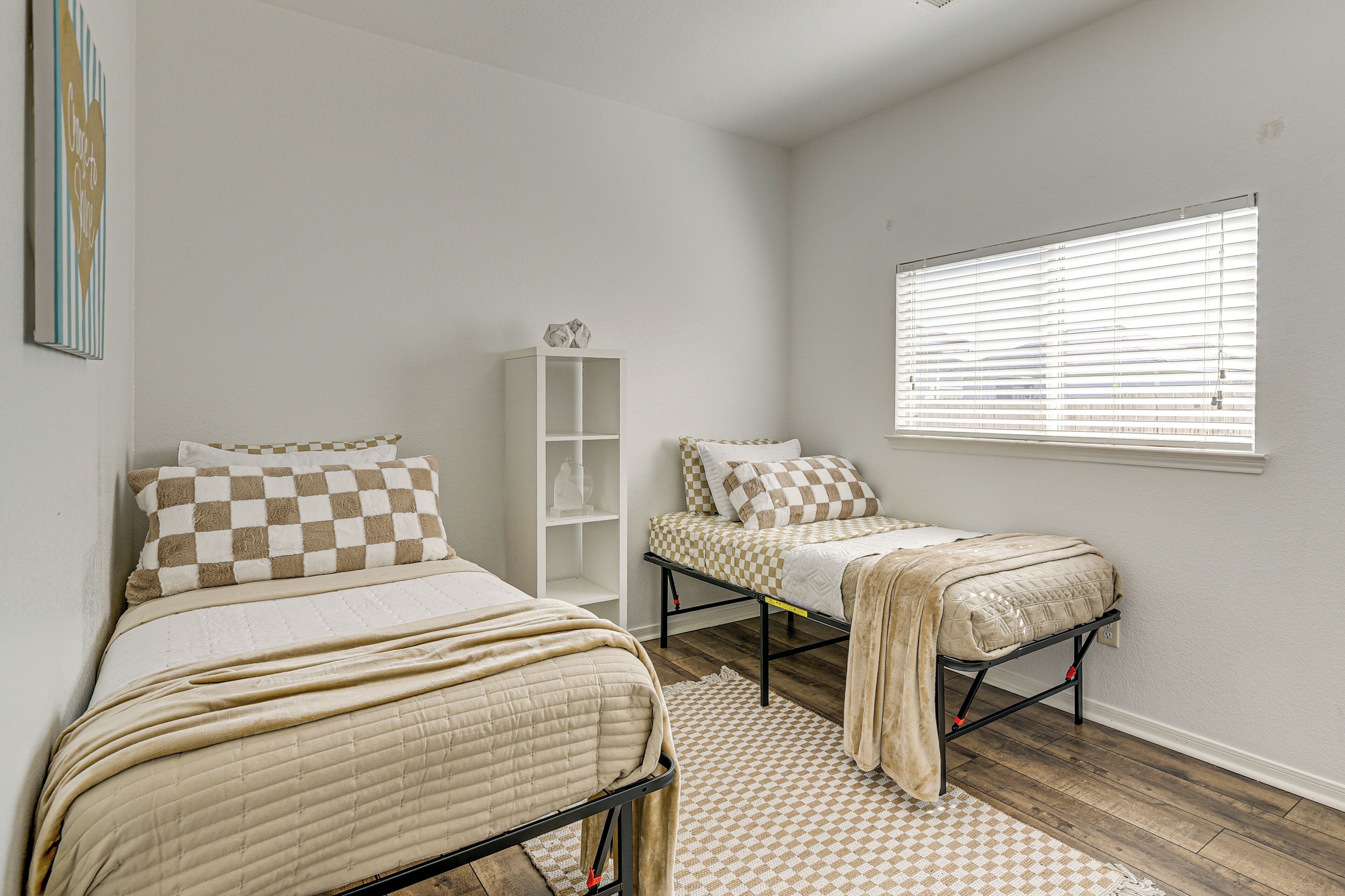 A bedroom with two beds, a white wardrobe, and a window with blinds.