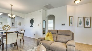 A living room with a beige sofa, a glass coffee table, and a dining area with a wooden table and chairs. - Family-friendly Houston Home: Soccer Fans Welcome! (Houston)