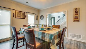 A dining area with a table set for four, wooden chairs, and a view of a staircase. - Residential Cul-de-sac: Suburban Memphis Hideaway! (Cordova)