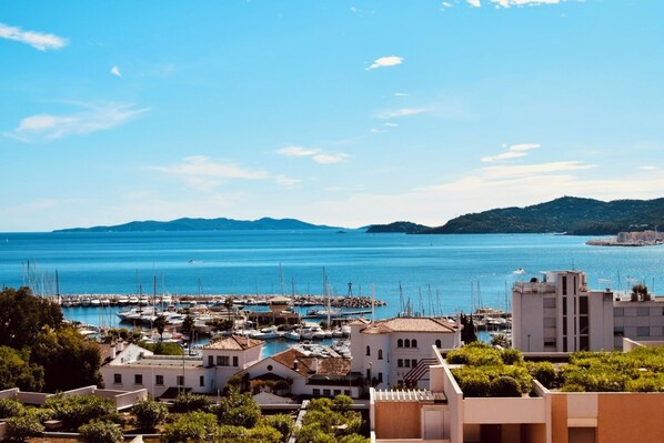 A marina with boats, a building with a tiled roof, and a mountainous backdrop. - Magnificent Grand STUDIO 28m2+ CLIM + sea view Terrace180- / south 8m2/+Box (Asc) (Le Lavandou)