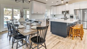 A modern kitchen with white cabinets, stainless steel appliances, a large island, and wooden bar stools. - Fully Furnished Poolside Oasis 5 Mi to Lake Havasu (Lake Havasu City)