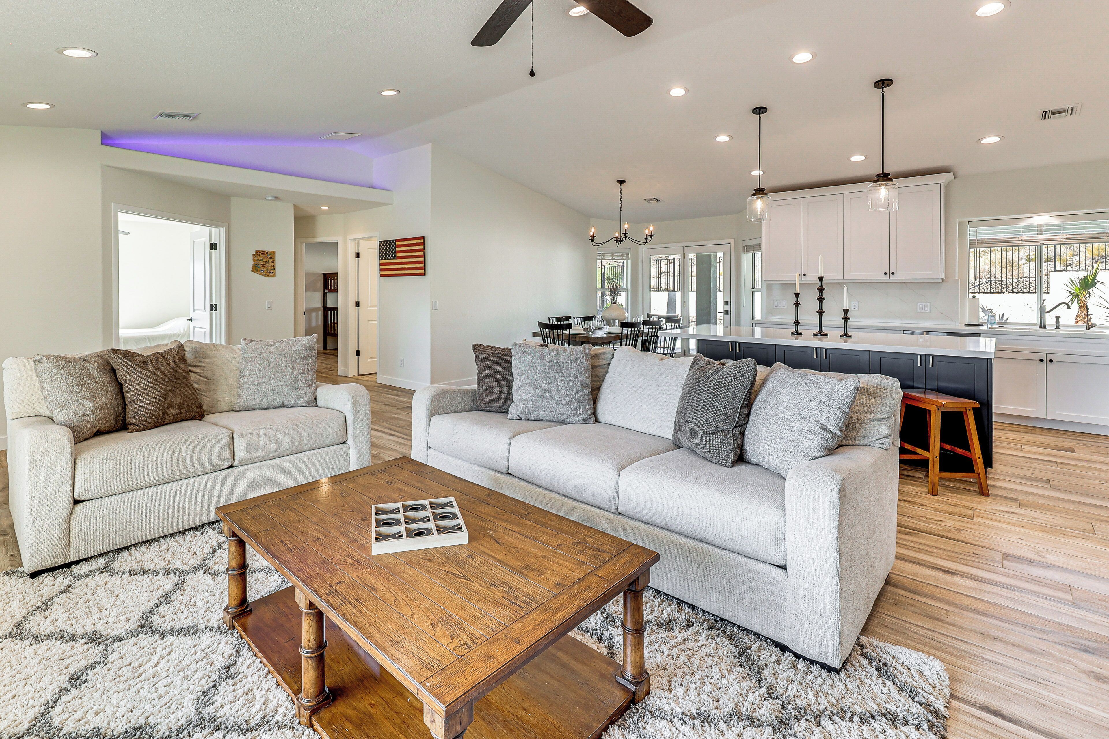 A spacious living room with two sofas, a coffee table, and a kitchen in the background.