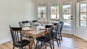 A dining area with a wooden table and black chairs, a white vase, and a chandelier. - Fully Furnished Poolside Oasis 5 Mi to Lake Havasu (Lake Havasu City)