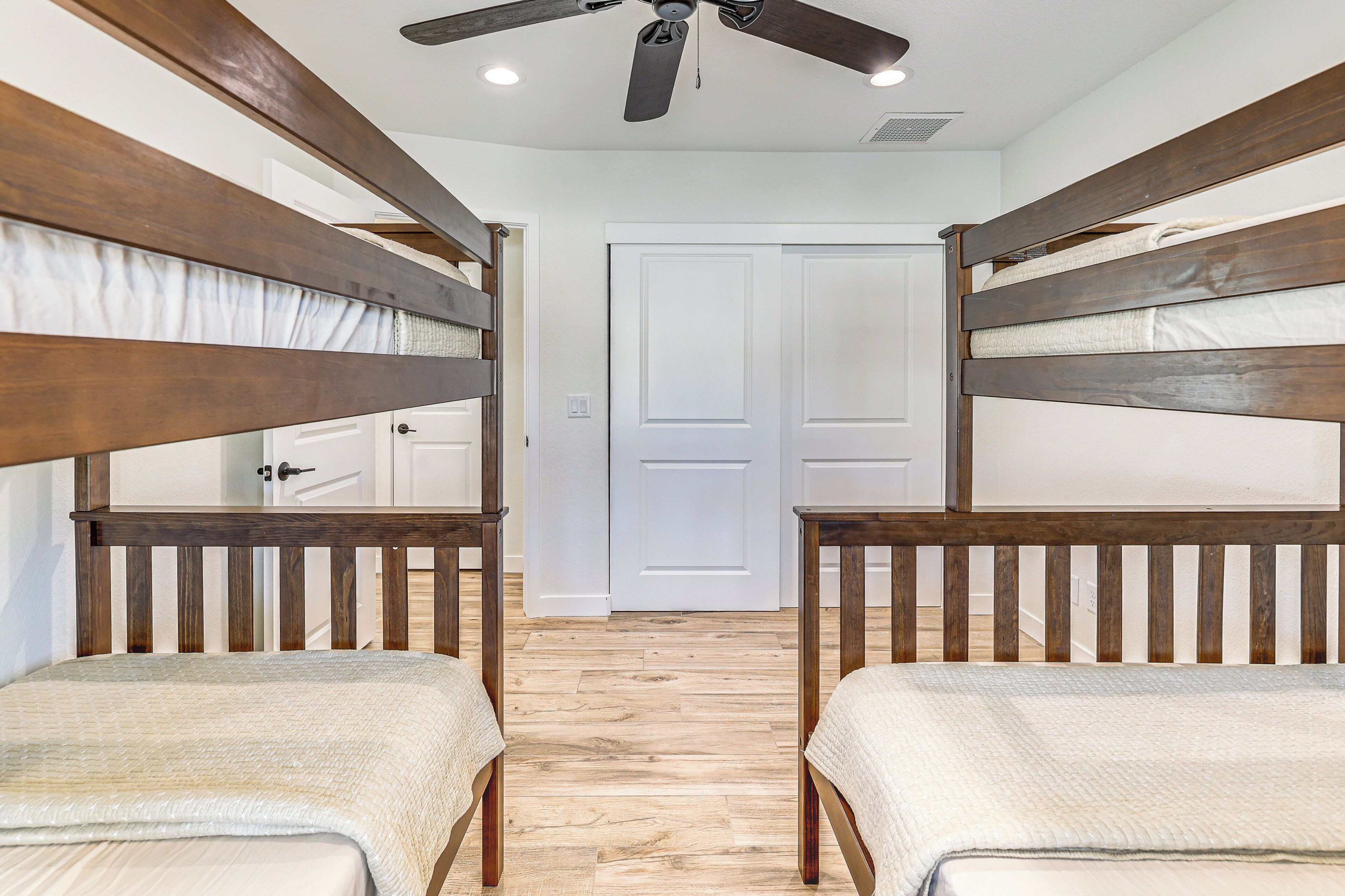 A room with two bunk beds, a ceiling fan, and a white door.