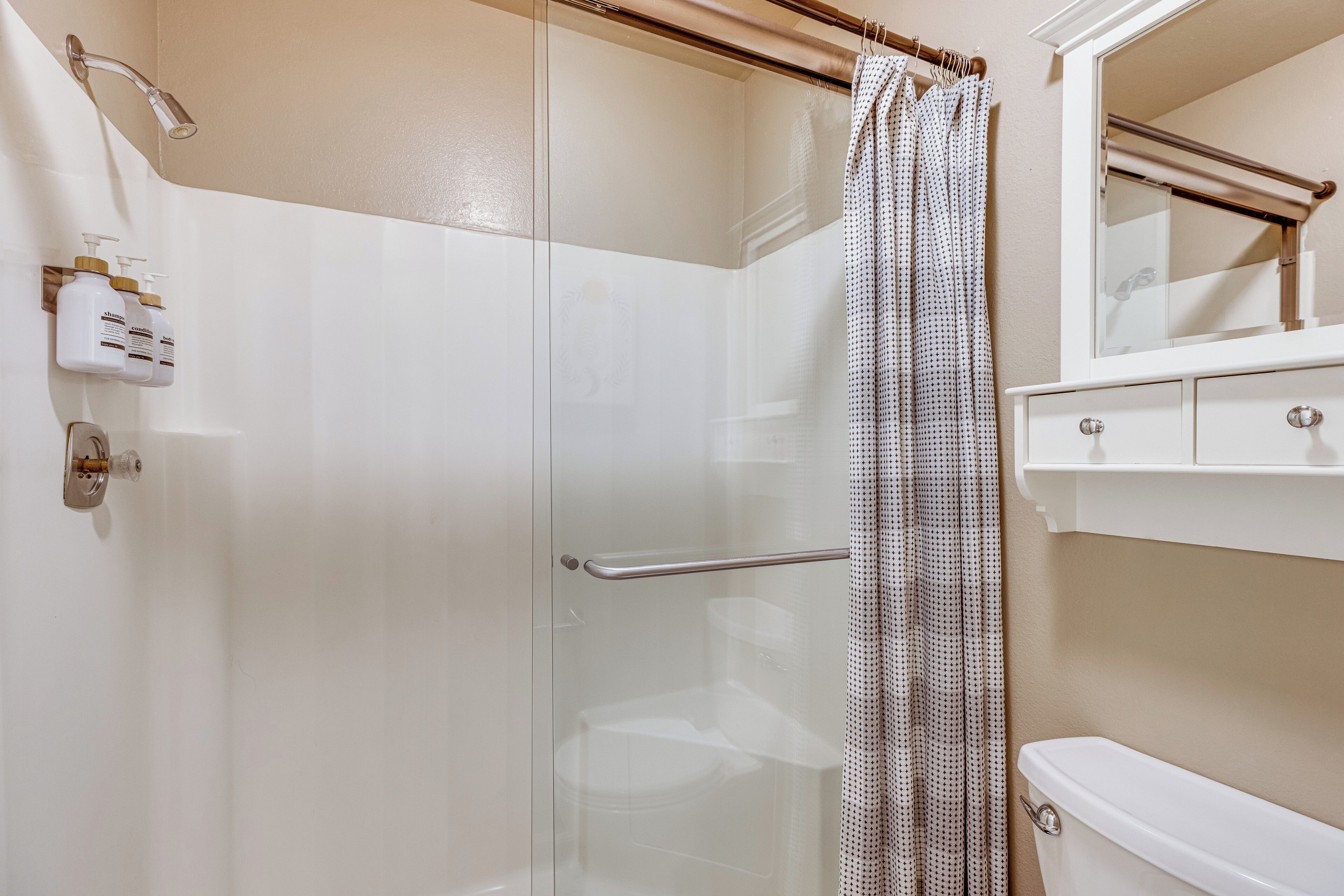 A modern bathroom with a glass shower enclosure, a toilet, a sink with a mirror, and a towel rack.