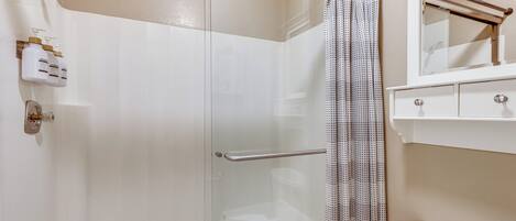 A modern bathroom with a glass shower enclosure, a toilet, a sink with a mirror, and a towel rack.