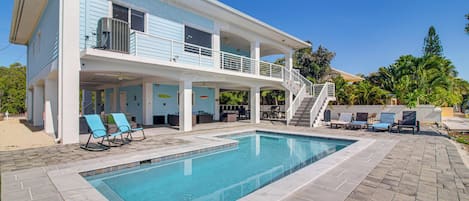 A two-story house with a swimming pool, outdoor seating, and a covered patio area.