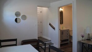 Un'area pranzo con tavolo e sedie, una scala che conduce al bagno e uno specchio a parete.