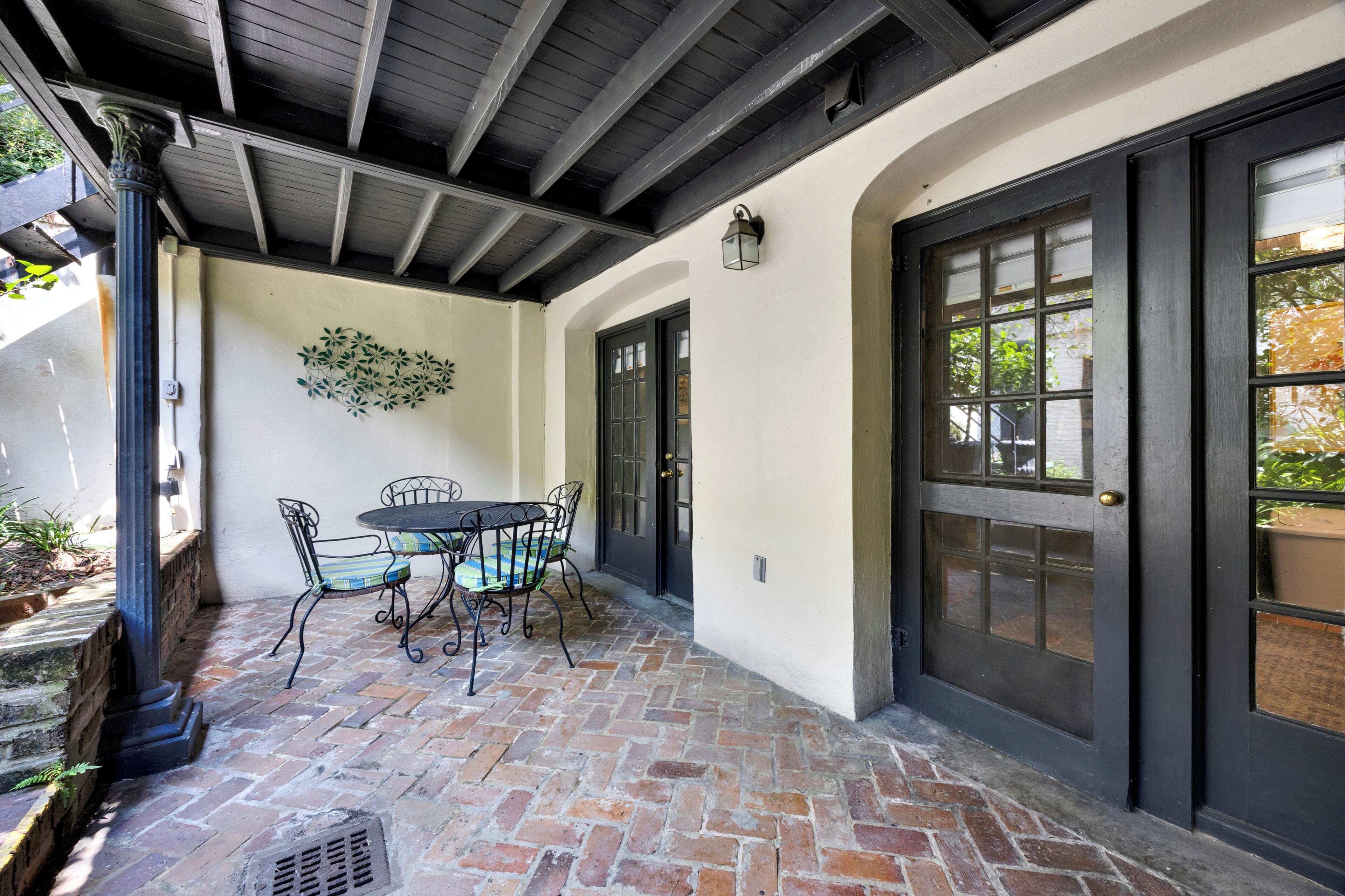 A patio with a brick floor, a table with chairs, and a decorative wall.