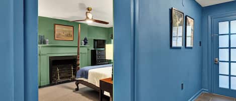 Een kamer met een open haard, een bed, een plafondventilator en een deur met gezoet glas.