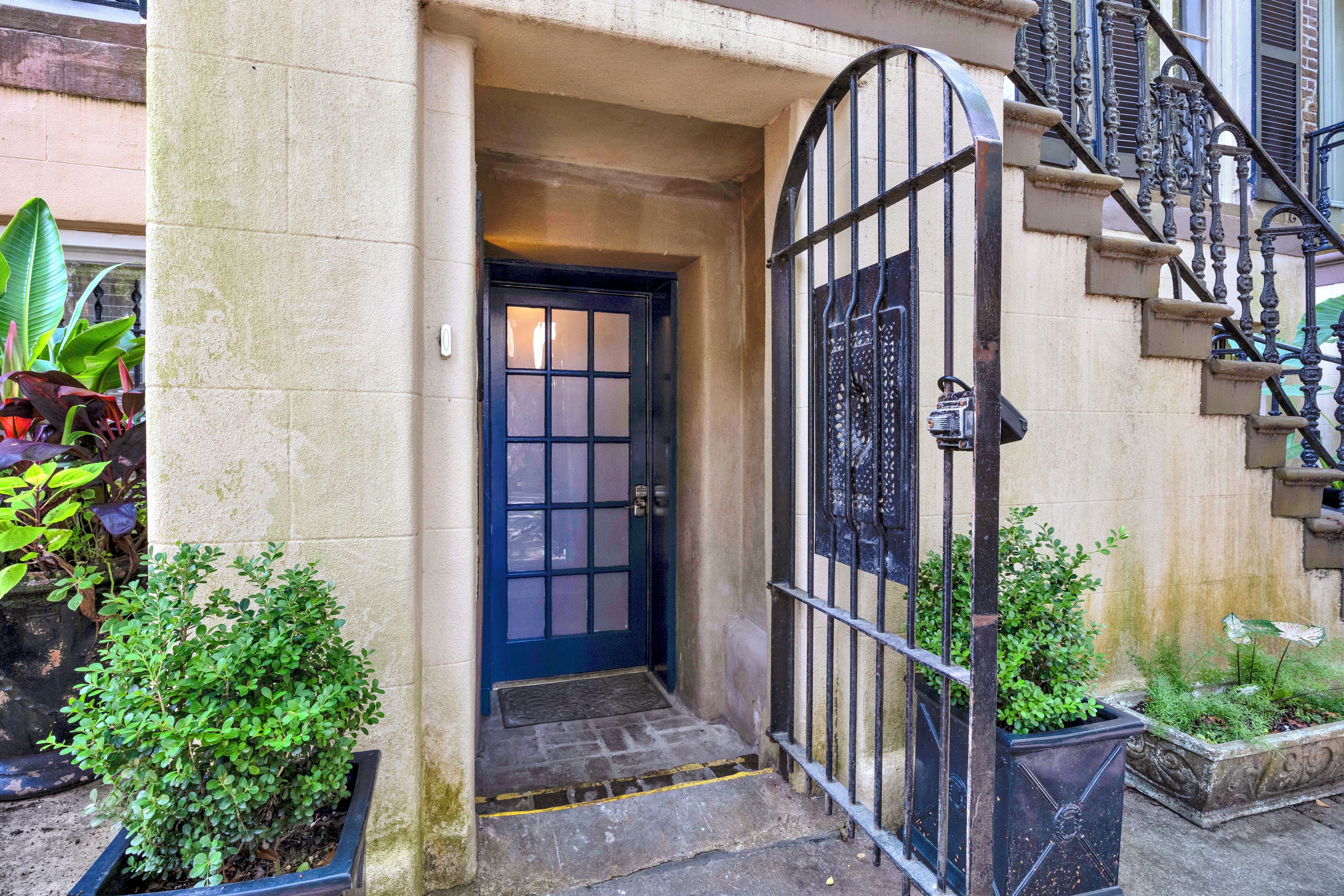 L’entrée d’un immeuble avec une porte bleue, un portail en métal et des marches menant à un escalier.