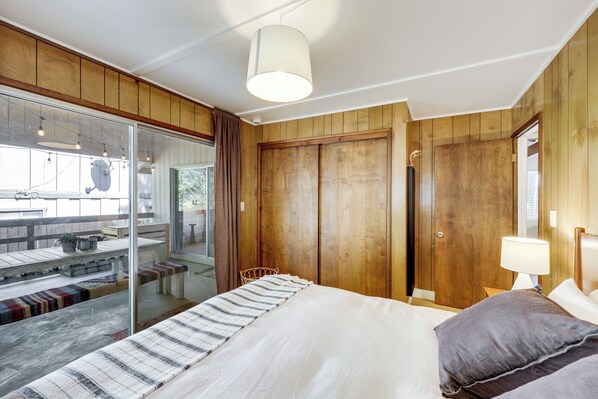 A bedroom with a bed, a bench, a table, and a door.