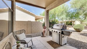 An outdoor patio with a grill, wicker furniture, and a potted plant. - Pool Access: Oakwood Home in Sun Lakes (Chandler)