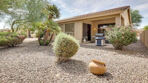 A house with a patio area, outdoor seating, and a small garden with various plants. - Pool Access: Oakwood Home in Sun Lakes (Chandler)