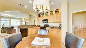 A spacious kitchen with wooden cabinets, a central island, and a dining area with a round table and chairs. - Pool Access: Oakwood Home in Sun Lakes (Chandler)