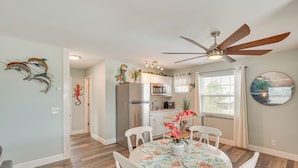 A dining area with a round table, white chairs, a ceiling fan, and a kitchen in the background. - 8 Mi to Beaches: Getaway w/ Pool in Panama City! (Panama City)
