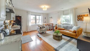 A modern living room with a sofa, coffee table, and kitchen area with cabinets and appliances. - Shop, Dine & Unwind: Dtwn Blowing Rock Retreat! (Blowing Rock)