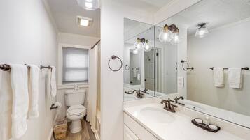 Un baño con un lavabo blanco, un espejo grande y un inodoro.